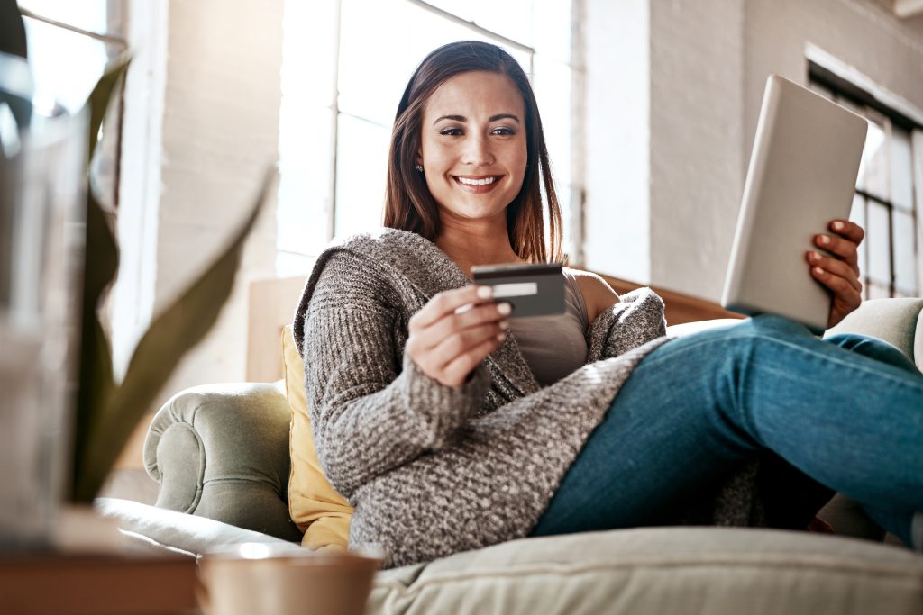 Online payment, digital tablet and credit card by woman on a sofa for online shopping in her home. Ecommerce, banking and girl with debit card for credit score, purchase or payment in living room